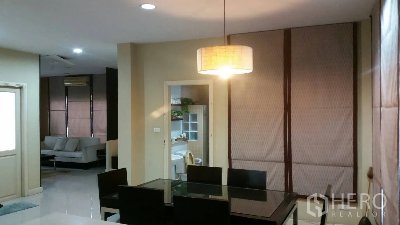 บ้าน ให้เช่าในLat Krabang, Bangkok - พื้นที่รับประทานอาหารแบบโอเพ่นแปลน มีโคมไฟแขวน โต๊ะกระจก และมุมมองไปยังห้องนั่งเล่นกับห้องน้ำ