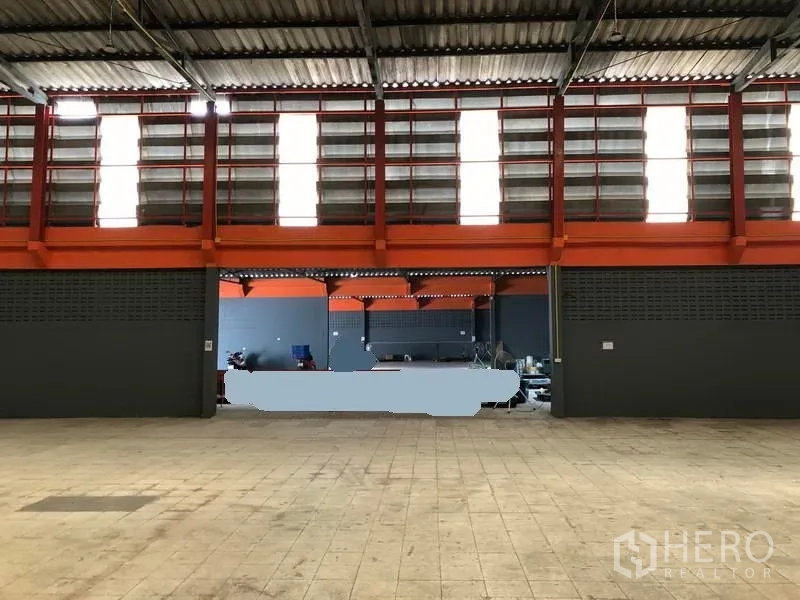 工厂 出租在Phra Pradaeng, Samut Prakan - 室内设有通风百叶窗与橙色梁柱，下方为开放作业区。