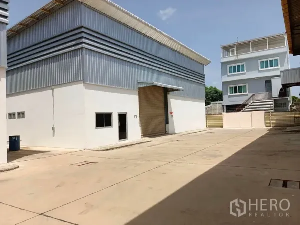 Warehouse for rent in Suan Luang, Bangkok - Modern warehouse exterior with a roller shutter and large paved loading yard.