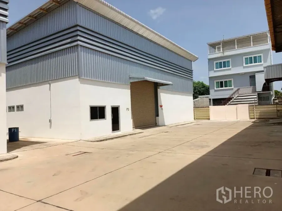 Warehouse for rent in Suan Luang, Bangkok - Modern warehouse exterior with a roller shutter and large paved loading yard.