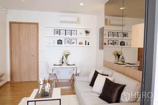 Condominium for sale in Watthana, Bangkok - Cozy living room with gray sofa, white dining set, wall shelves and wood flooring.