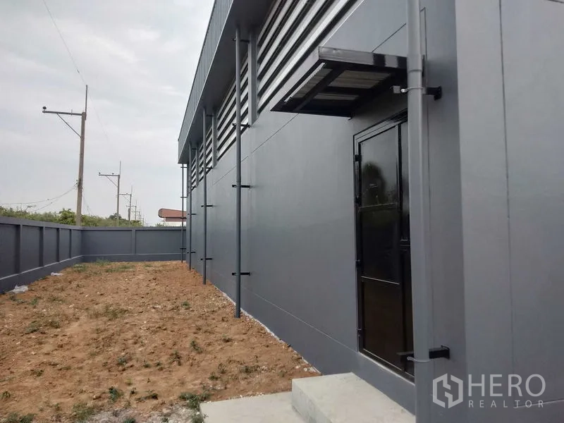 工厂 出租或出售 - 厂房侧立面，服务门与围墙庭院。