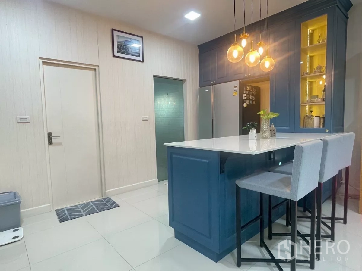 Detached House for sale in Bang Phli, Samut Prakan - Kitchen island facing pantry and side doors over bright tiled flooring.