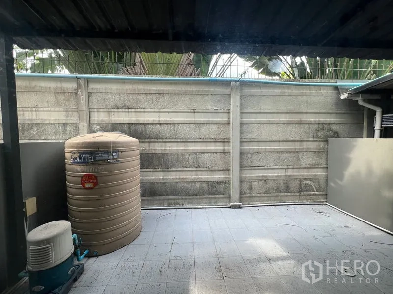 Townhouse for rent in Bang Kapi, Bangkok - Rear utility patio with water tank and pump under roof.