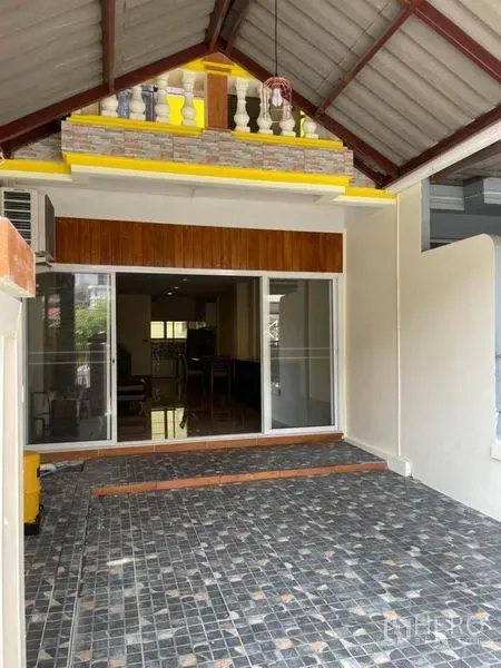 联排别墅 出租在Bang Na, Bangkok - 邦纳联排别墅前方带顶车位，铺石材地面并配滑动玻璃门入口。