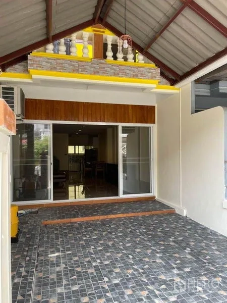 联排别墅 出租在Bang Na, Bangkok - 邦纳联排别墅前方带顶车位，铺石材地面并配滑动玻璃门入口。