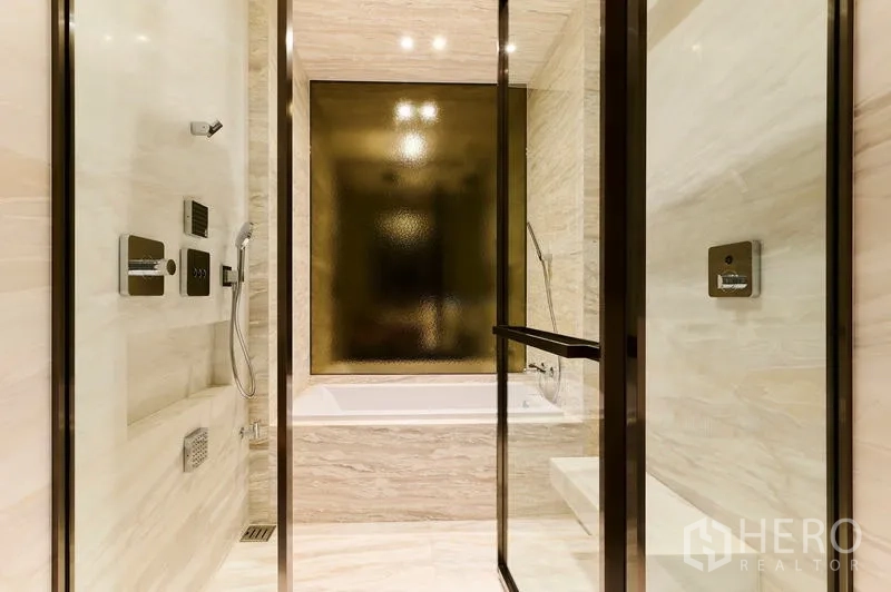 Condominium for rent in Pathum Wan, Bangkok - Marble bathroom with glass-enclosed shower and a separate bathtub.