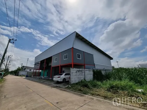 คลังสินค้า ให้เช่าในLam Luk Ka, Pathum Thani - มุมมองริมถนนของโกดังผนังเมทัลชีท ติดถนนทางเข้ากว้างและเสาไฟฟ้า