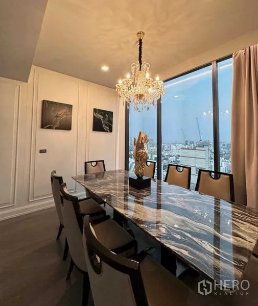 Condominium for rent in Watthana, Bangkok - Dining area with crystal chandelier above a veined marble table beside a tall window.