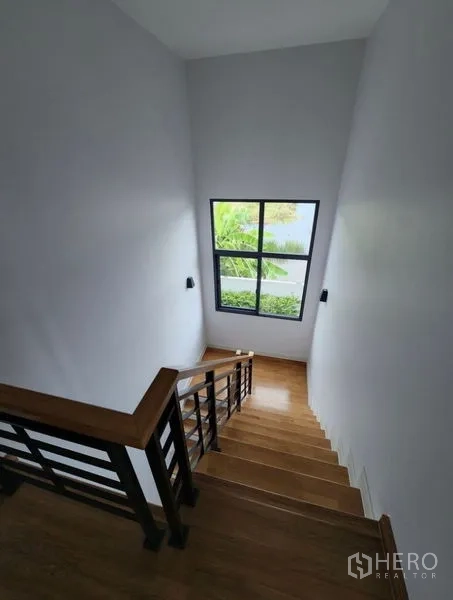 Detached House for rent in Bang Phli, Samut Prakan - Wood staircase with metal railing and a large window bringing natural light.