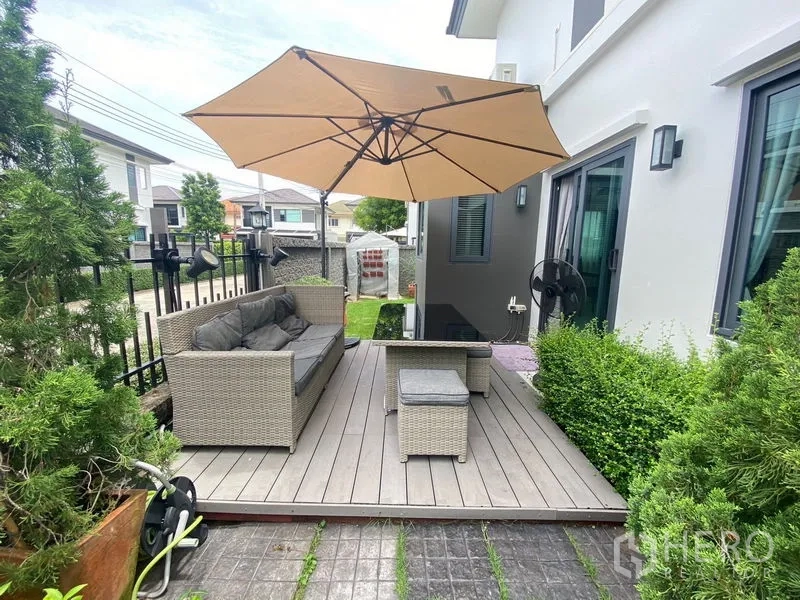 Detached House for rent in Bang Phli, Samut Prakan - Outdoor deck terrace with rattan sofa set and large umbrella beside sliding doors.
