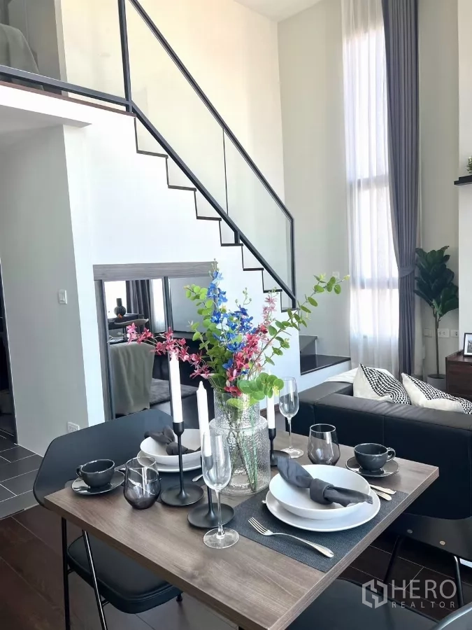 Condominium for rent in Watthana, Bangkok - Set dining table with glassware beside stairs to the mezzanine bedroom.
