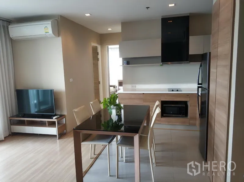 คอนโด ให้เช่าในPhaya Thai, Bangkok - ครัวและโซนทานอาหารแบบเปิด โทนไม้พร้อมโต๊ะกระจกและมุมทีวีในคอนโดสมัยใหม่