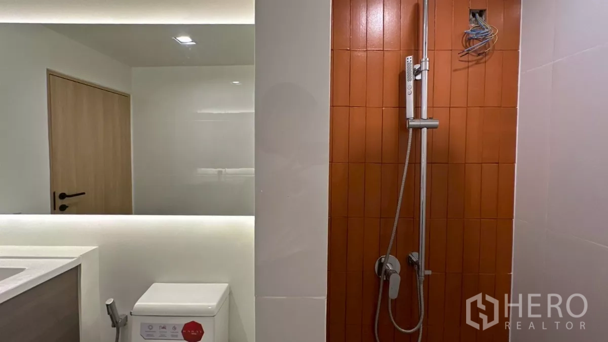Home Office for rent in Watthana, Bangkok - Shower zone with handheld set beside vertical orange tile feature and toilet.