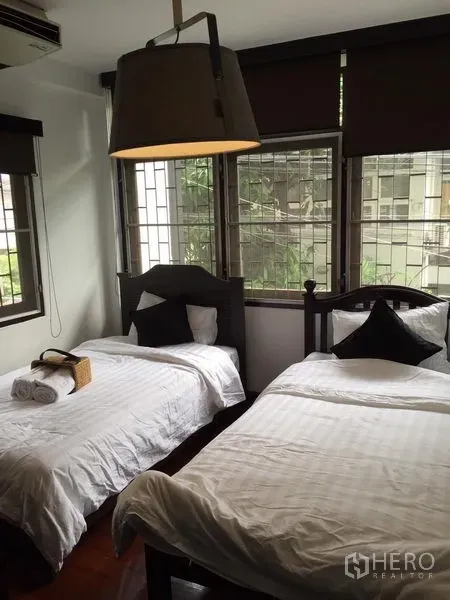 บ้าน ให้เช่าในWatthana, Bangkok - ห้องนอนสว่างด้วยหน้าต่างมุมห้อง เตียงเดี่ยวคู่ และโคมไฟแขวนขนาดใหญ่