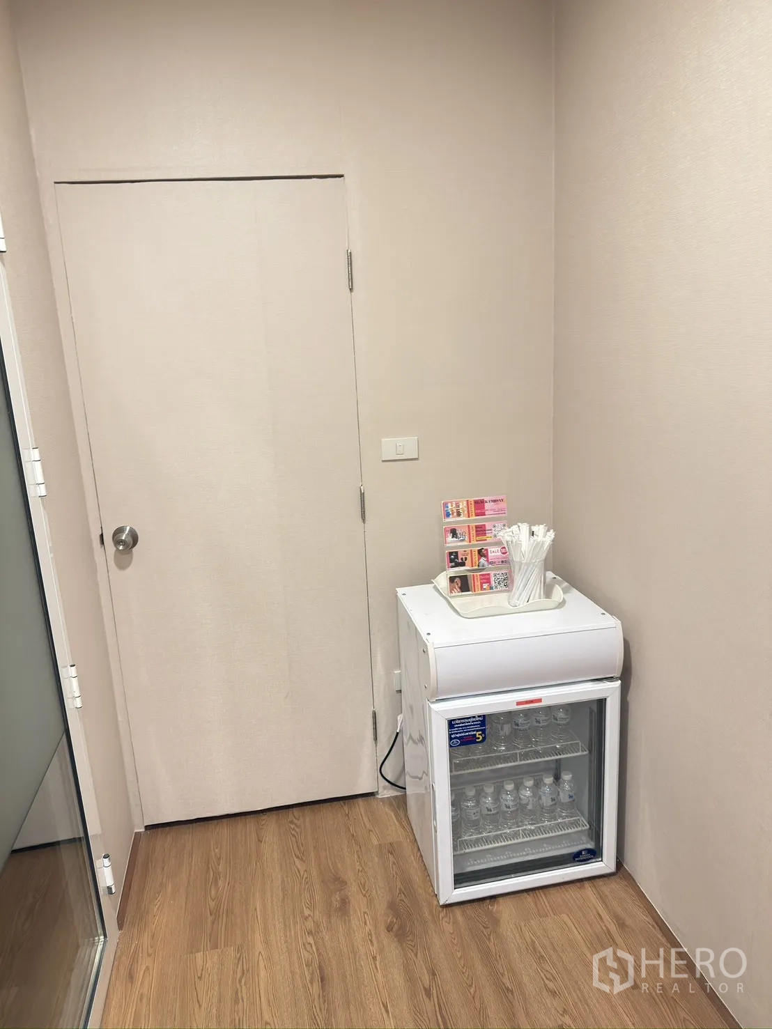 Retail Space for rent in Khlong Toei, Bangkok - Compact beverage fridge with bottled water beside an interior door in the corridor.