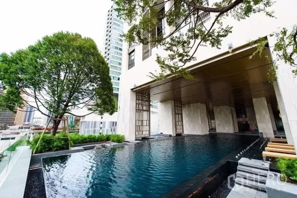 Condominium for rent or sale in Watthana, Bangkok - Elevated outdoor swimming pool beside a luxury condominium facade with trees and city views in Bangkok.