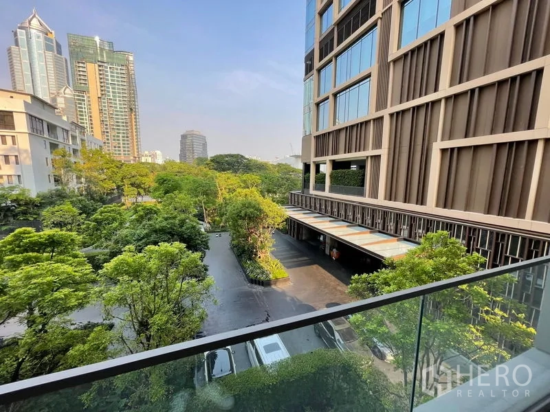 Condominium for rent or sale in Pathum Wan, Bangkok - Balcony view of landscaped courtyard, modern building facade and Bangkok skyline.