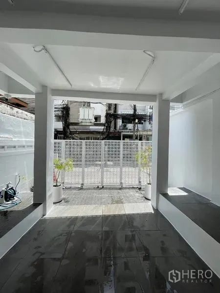 店屋 出售在Din Daeng, Bangkok - 丁当曼谷翻新白色店屋的前廊与金属栅栏大门，瓷砖地面和绿植。