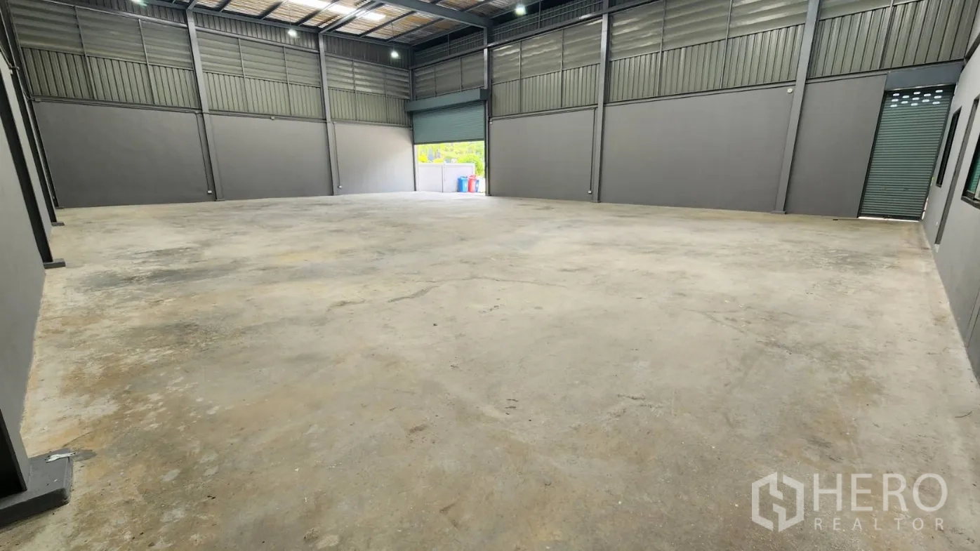 Factory for rent in Bang Bo, Samut Prakan - Empty warehouse showing two roller doors, steel-clad walls and a high ceiling.