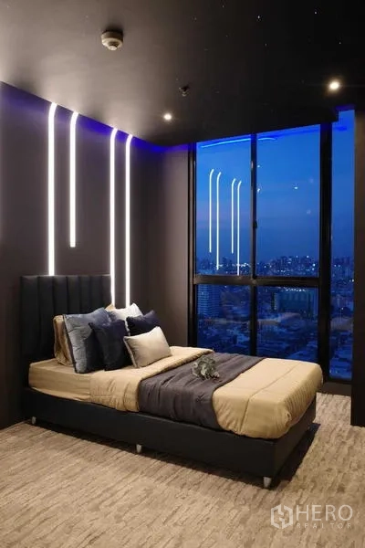 คอนโด ขาย - ห้องนอนโมเดิร์นไฟตกแต่งและหน้าต่างเต็มบาน เห็นเส้นขอบฟ้าใจกลางกรุงเทพยามค่ำ