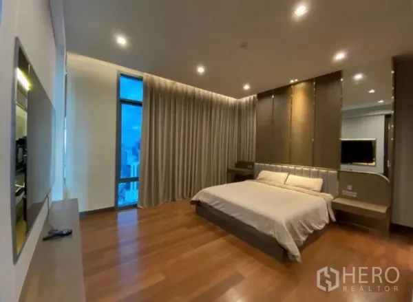 公寓 出租在Khlong Toei, Bangkok - 宽敞主卧，木地板、嵌灯，落地窗配长窗帘，城市景观。