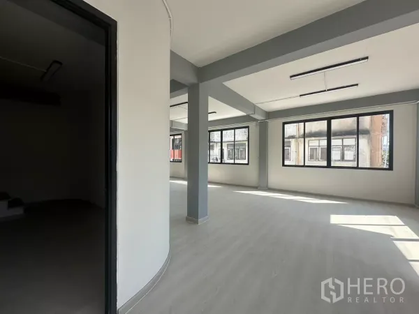 办公空间 出租在Phra Khanong, Bangkok - 开放办公区与一侧会议室入口，可见立柱与双排窗户。