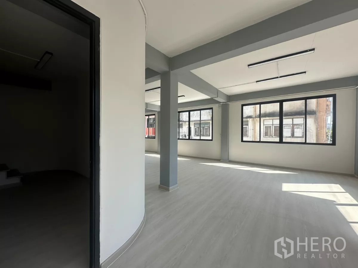 办公空间 出租在Phra Khanong, Bangkok - 开放办公区与一侧会议室入口，可见立柱与双排窗户。
