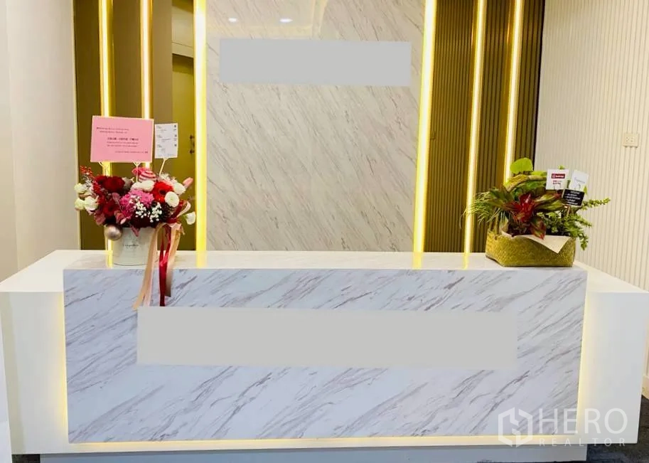 Office Space for rent in Sathon, Bangkok - Marble reception desk with warm backlit panels and floral arrangements.
