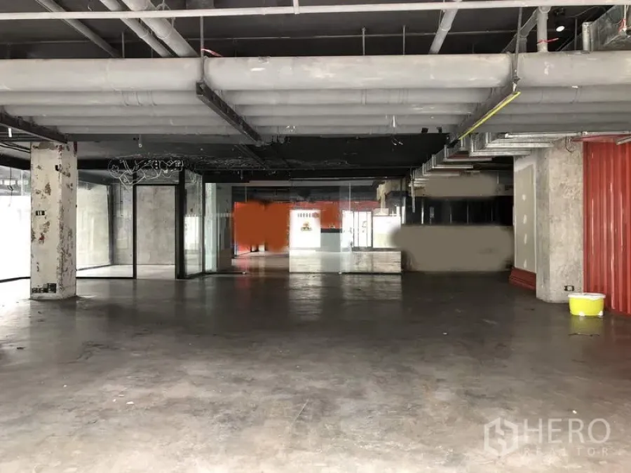 零售空间 出租在Khlong Toei, Bangkok - 开放式商业空间，高挑天花与大型玻璃门面，工业风管线。