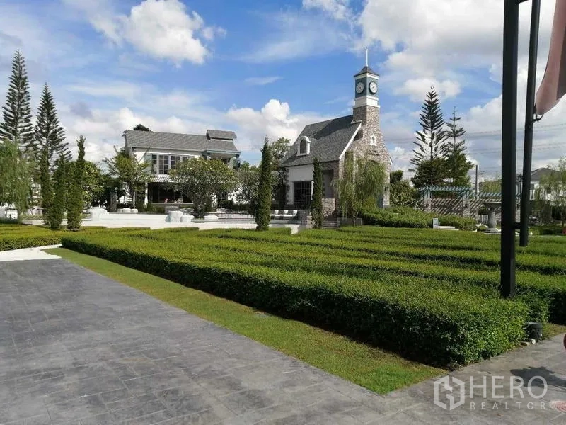 Townhouse for rent - Community clubhouse with clock tower, manicured hedges, and open green park.
