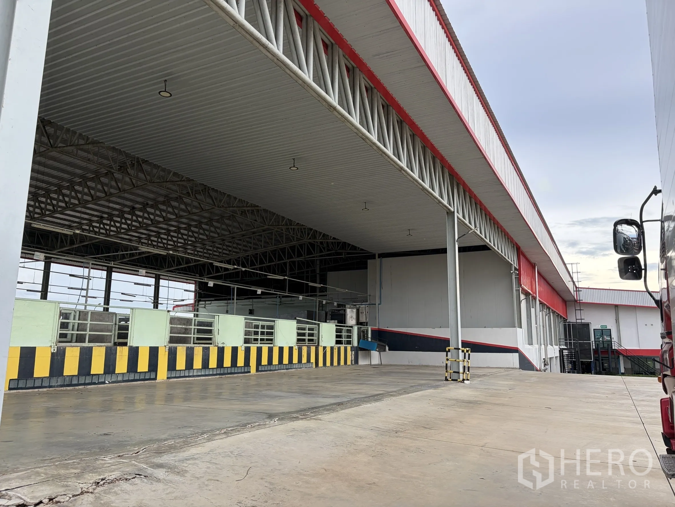Factory for sale in Mueang Nakhon Pathom, Nakhon Pathom - Covered processing or loading area with steel truss roof and safety barriers.