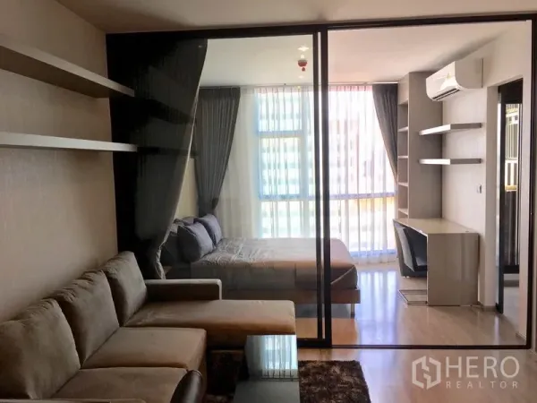 คอนโด ให้เช่าในWatthana, Bangkok - ห้องนั่งเล่นและห้องนอนกั้นด้วยผนังกระจก มีโซฟาสีเทาและหน้าต่างสูงจรดเพดาน