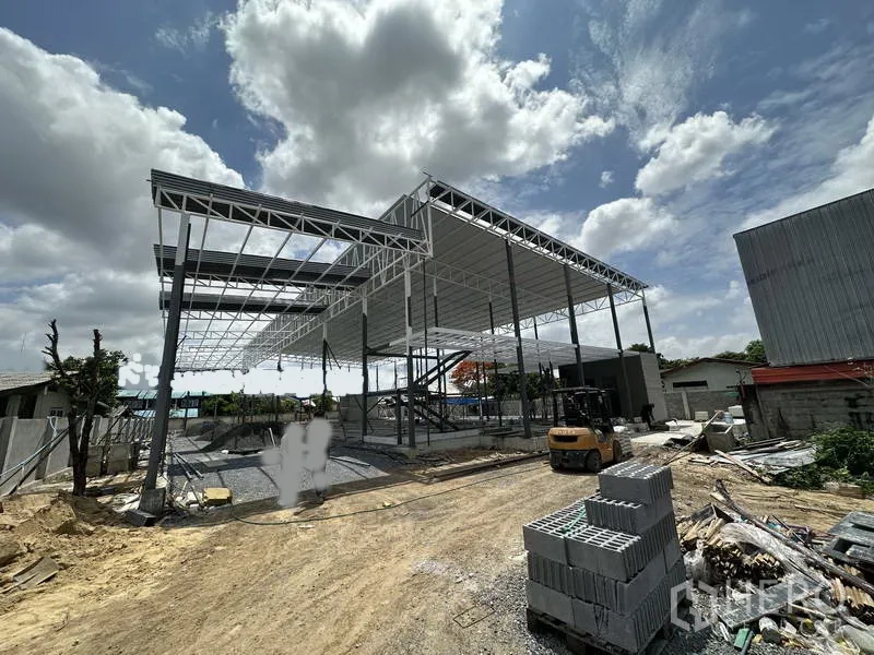 货栈 出租在Lat Krabang, Bangkok - 仓库正面部分屋顶已完成，现场有叉车与堆放的建材。
