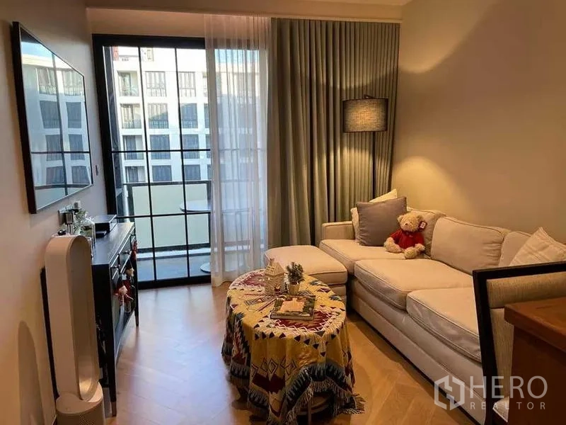 Condominium for rent or sale - Living room facing balcony with floor-to-ceiling curtains and TV wall