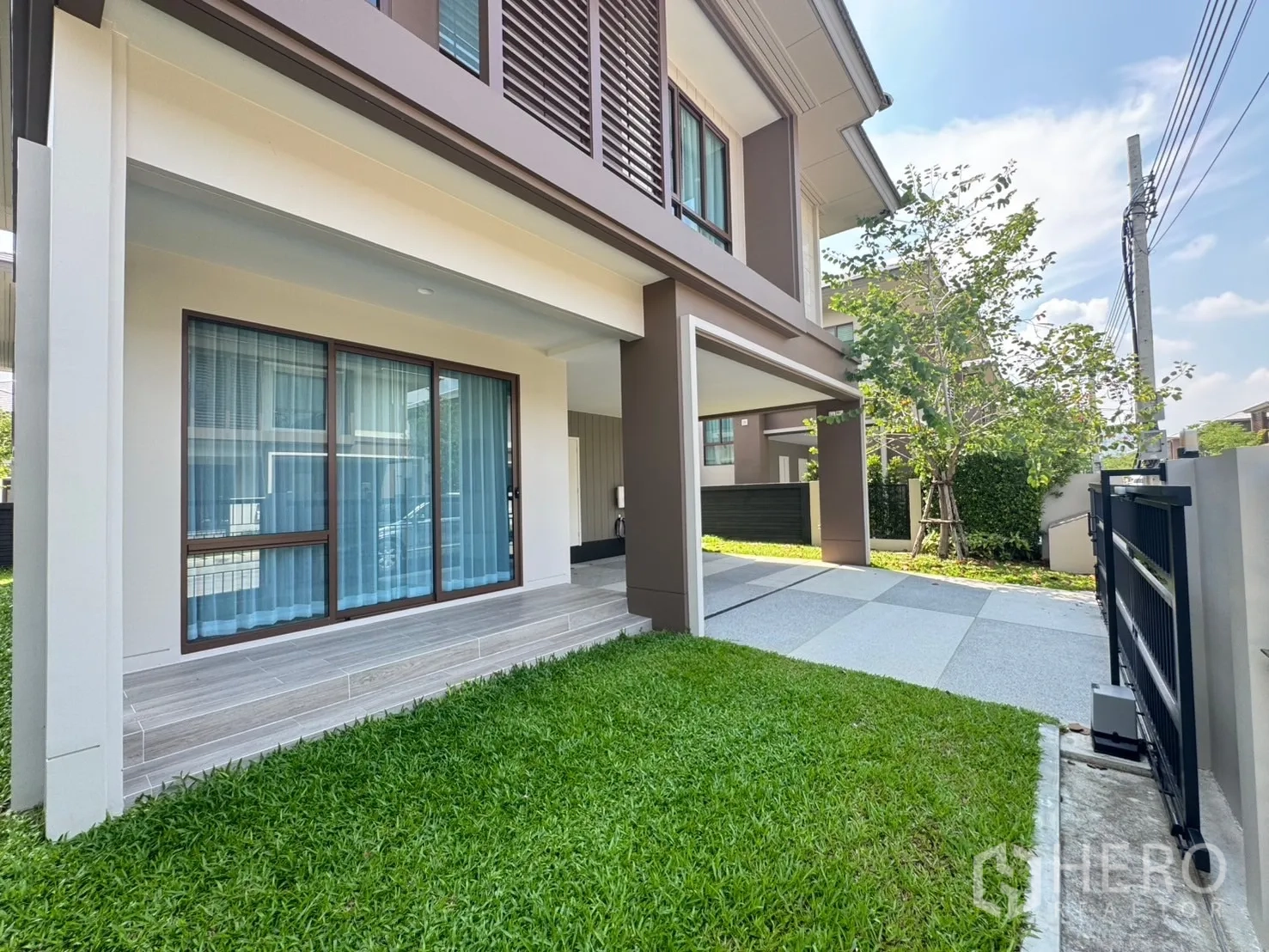 บ้าน ให้เช่าหรือขายในBang Kapi, Bangkok - สนามหญ้าหน้าบ้านและชานระเบียง เชื่อมสู่ที่จอดรถในร่มและประตูกระจกบานเลื่อน