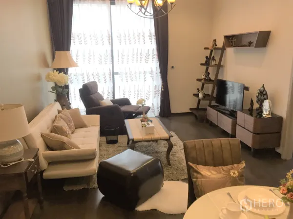 คอนโด ให้เช่าในWatthana, Bangkok - ห้องนั่งเล่นโทนอุ่น พื้นไม้ โซฟา ชั้นวางทีวี ผ้าม่านโปร่งและหน้าต่างสูง