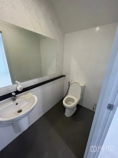 带办公室的家 出租 - 客用卫生间，长镜子与白色洗手盆，灰色地砖搭配马桶。