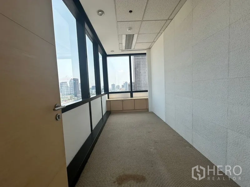 Office Space for rent in Khlong Toei, Bangkok - Narrow manager’s room with wraparound windows and city outlook, carpeted floor.