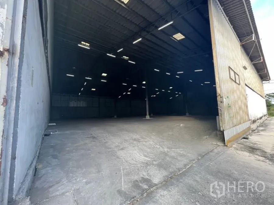 คลังสินค้า ให้เช่าในBang Sao Thong, Samut Prakan - ประตูทางเข้ากว้างเห็นภายในโกดังเพดานสูง พื้นคอนกรีตและไฟ LED