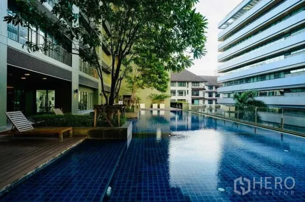 公寓 出租在Watthana, Bangkok - 户外游泳池，躺椅、绿树与周围的现代楼栋。