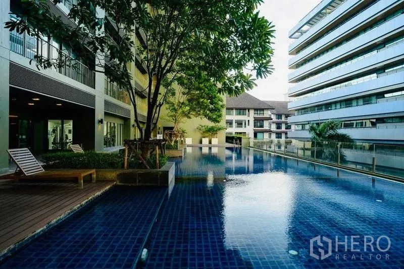 公寓 出租在Watthana, Bangkok - 户外游泳池，躺椅、绿树与周围的现代楼栋。