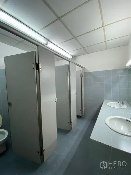 办公空间 出租 - 整洁的共享洗手间，灰色瓷砖，多个隔间与双人台盆。