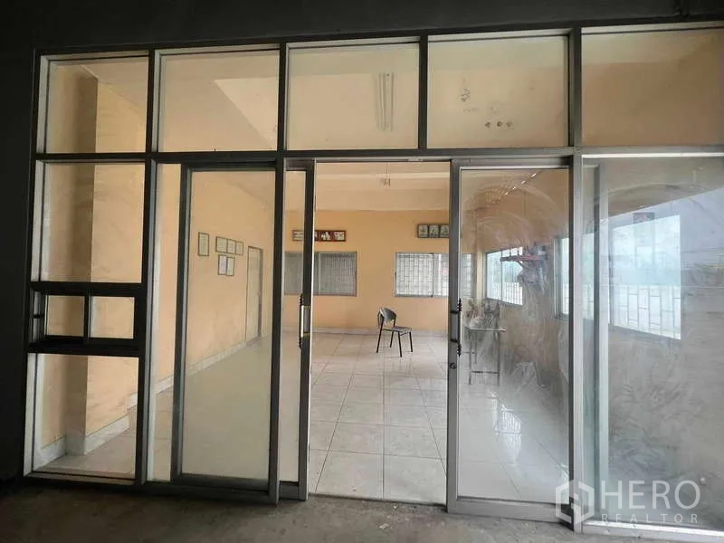 Warehouse for rent in Lam Luk Ka, Pathum Thani - Glass-fronted office entrance with sliding doors opening to a tiled room.