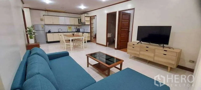 คอนโด ให้เช่าในKhlong Toei, Bangkok - ห้องนั่งเล่นแบบเปิดกว้าง โซฟาสีฟ้า ทีวีบนตู้ไม้ โต๊ะทานอาหารและครัวด้านหลัง