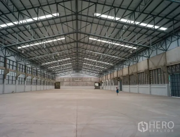 Factory for rent in Pathum Thani - Expansive clear-span production floor under a metal roof with ventilation panels.