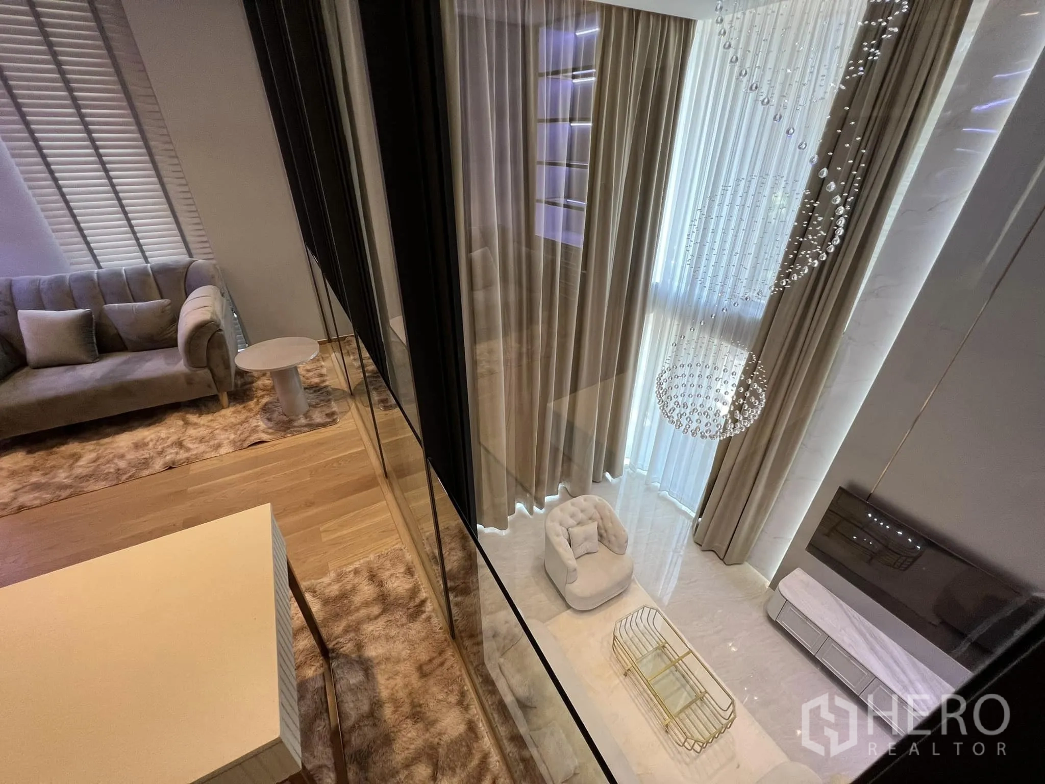 บ้าน ให้เช่าหรือขายในYan Nawa, Bangkok - มุมมองจากชั้นลอยลงสู่ห้องนั่งเล่นเพดานสูงและโคมไฟคริสตัล