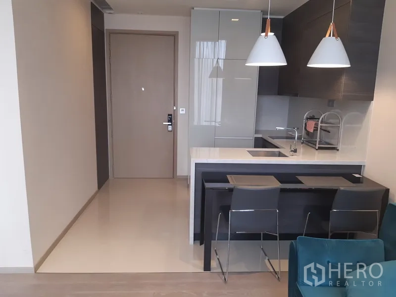 Condominium for rent or sale in Watthana, Bangkok - Entryway leading to sleek kitchen with breakfast bar, pendant lights and integrated storage.