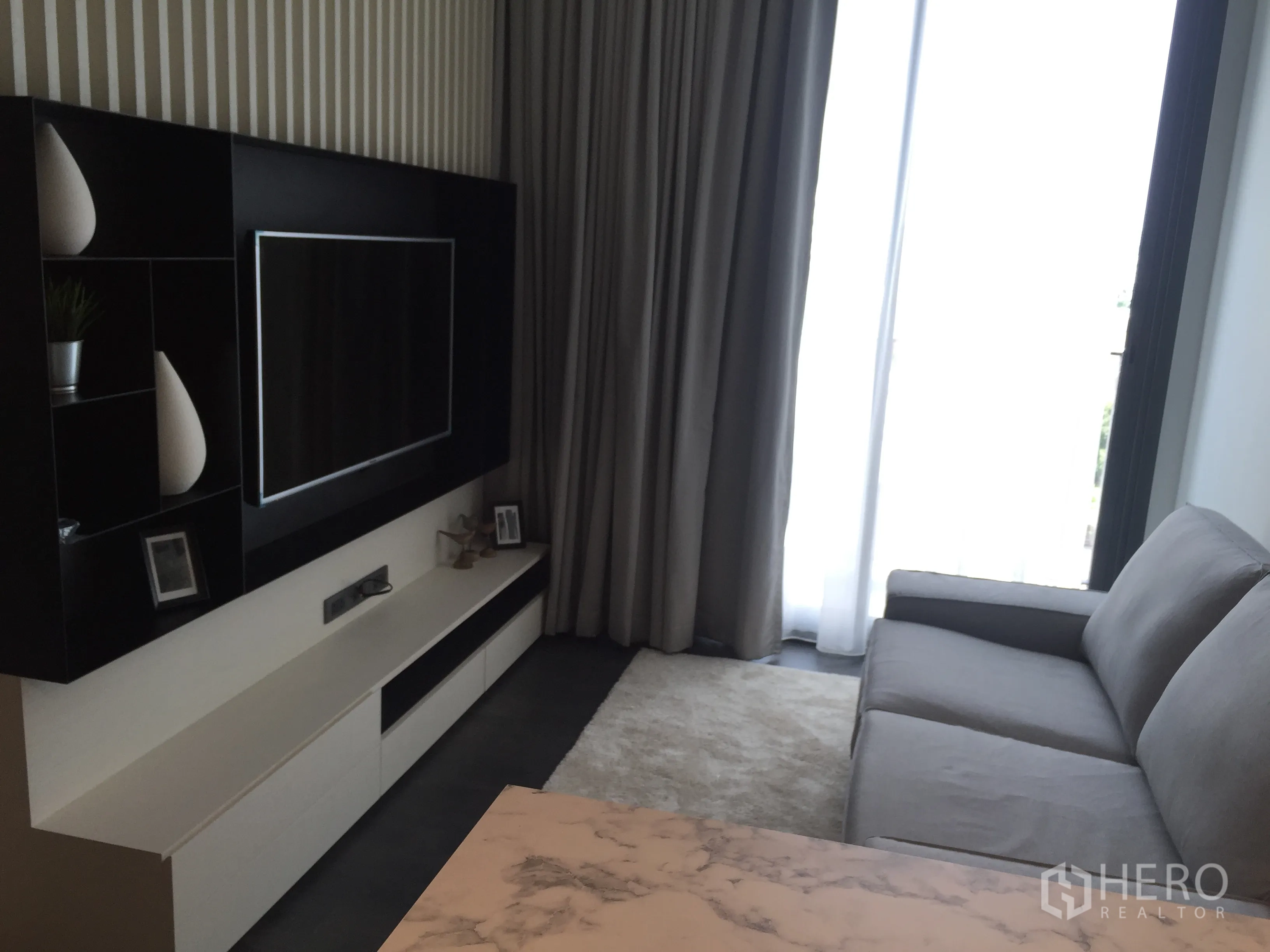 公寓 出租在Watthana, Bangkok - 客厅配沙发、壁挂电视、阳台推拉门与大理石台面。