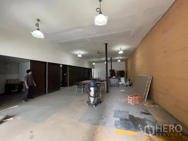 Warehouse for rent in Suan Luang, Bangkok - Spacious storage hall with central columns, sliding side rooms for office or stock, and durable concrete floors.